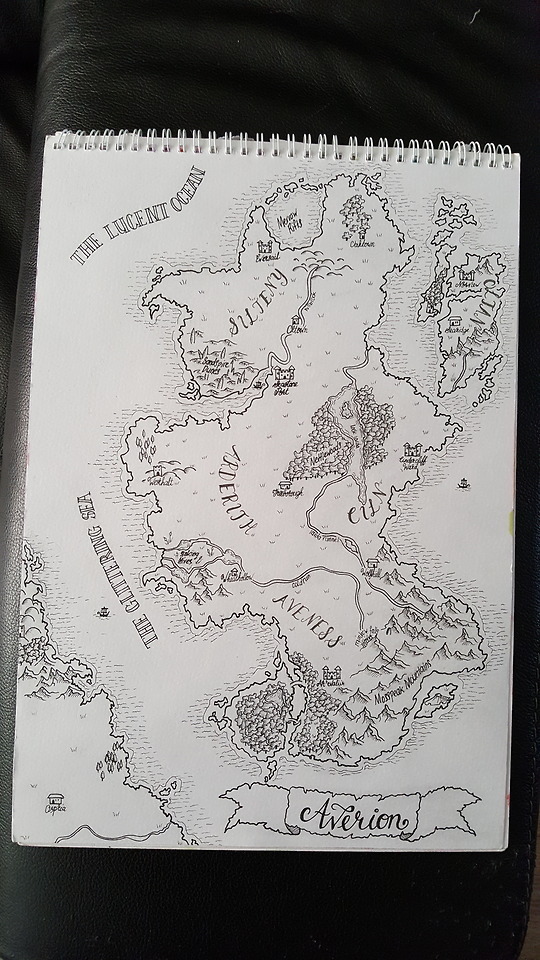 a photo of a sketchpad laying on a black surface. On the pad a map is drawn in black ink