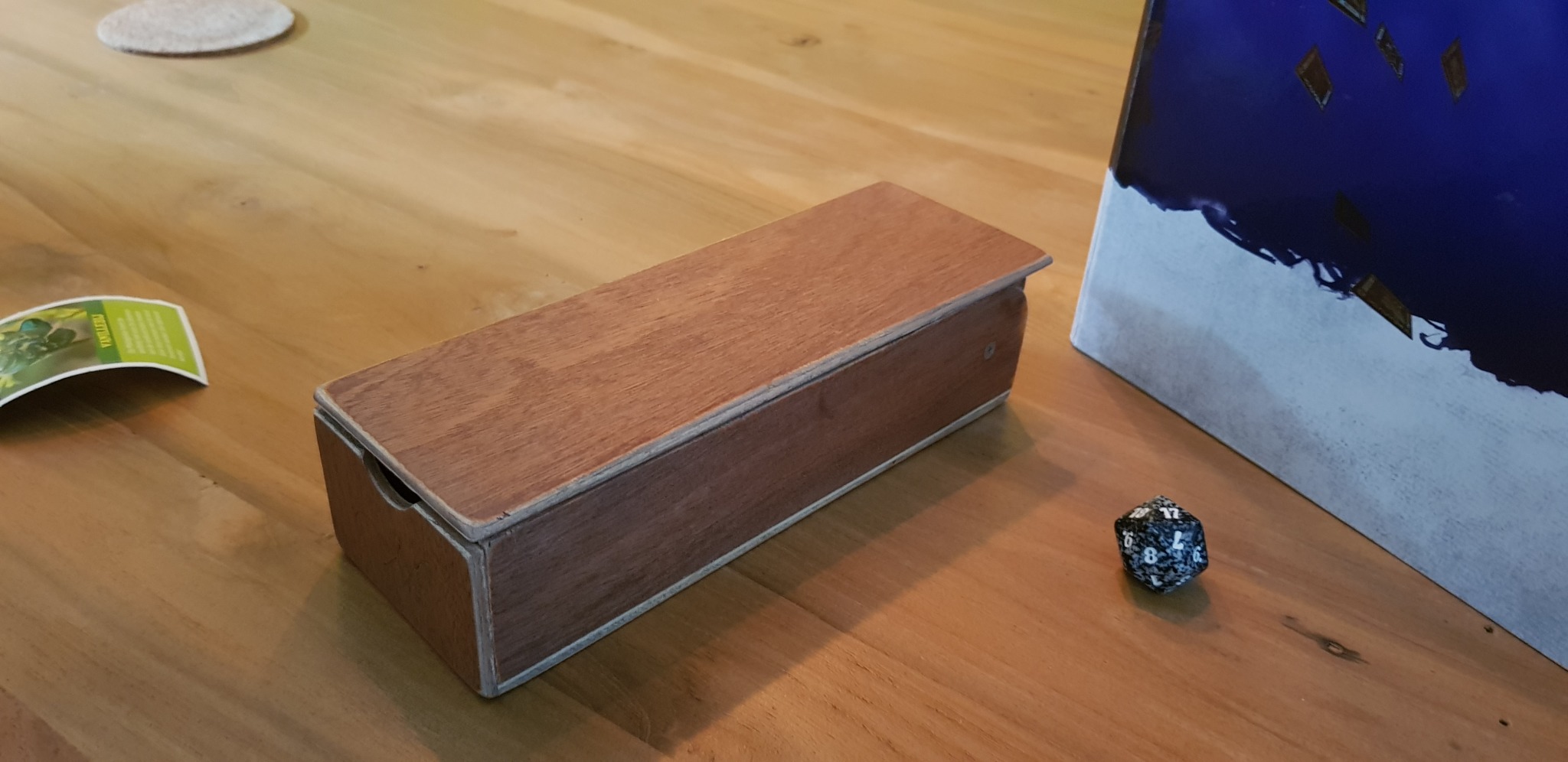 a wooden dice tower standing on a table, folded closed
