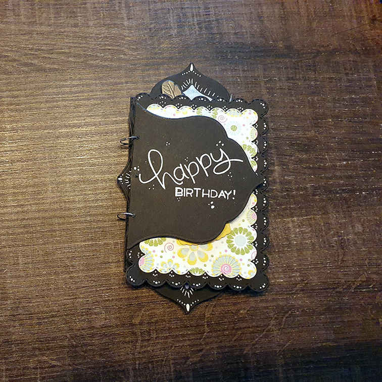 the front card of a set of birthday cards which are bound together like a booklet. The card is black, the text is white and reads: Happy Birthday!
