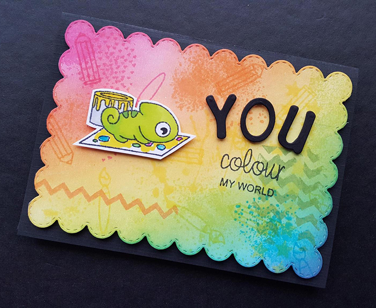 a card with a rainbow background. A stamp of a chameleon working on a painting sits on the left, and on the write is written You colour my world.