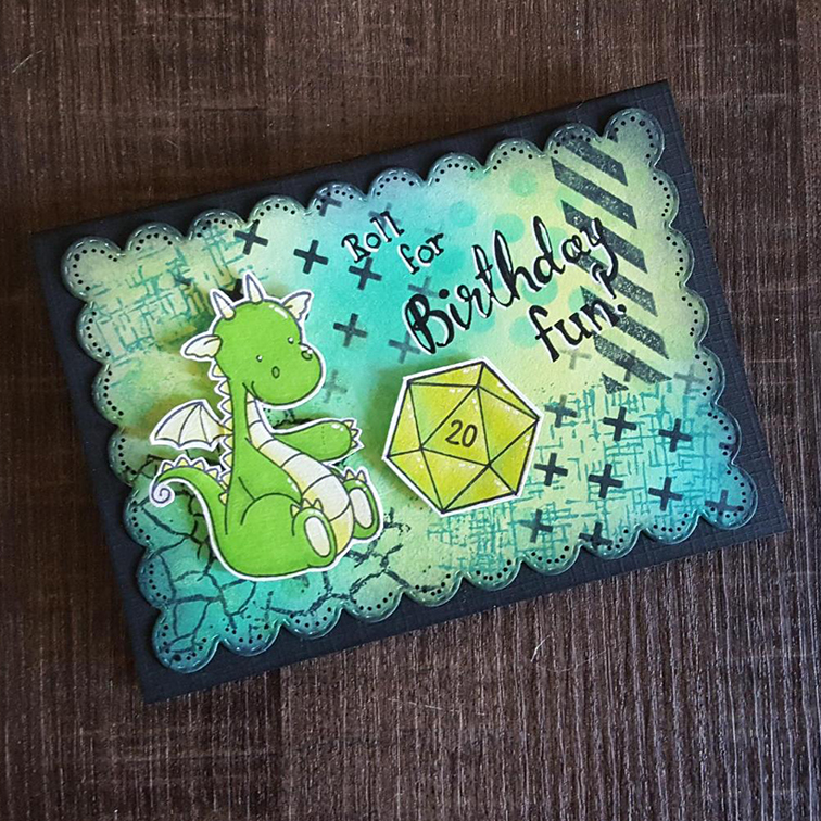 A black card with a blue and green background. A green stamped dragon is pointing to a lime green D20, resting with the 20 visible. The text says Roll for Birthday Fun!