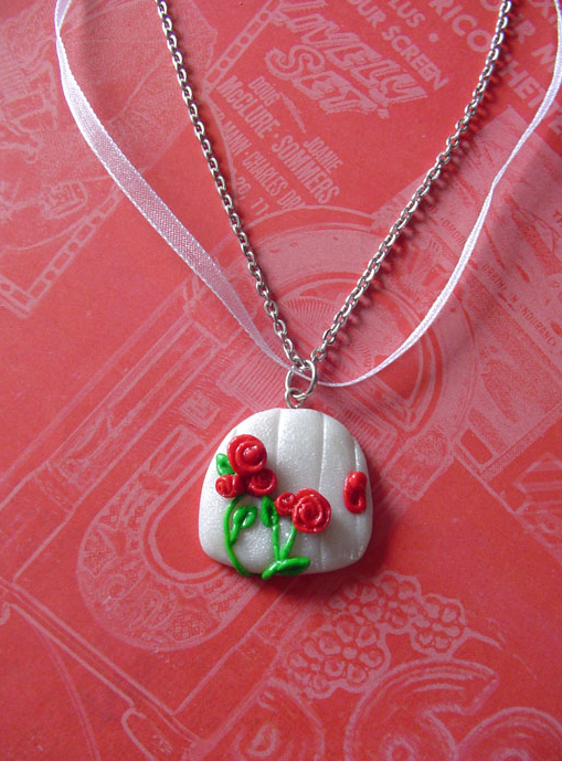 A necklace of silver chain and white ribbon. The pendant is a small white faerie door, with a red rose on it.