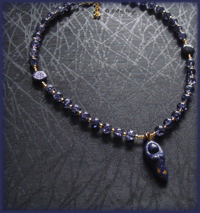 A beaded necklace with shimmering blue and gold beads. A small blue goddess pendant hangs at the centre.